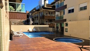 Un área de piscina en la azotea con varias piscinas y sillones de descanso.