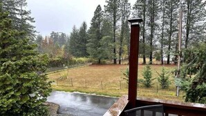 A wooden deck with a metal railing overlooking a fenced yard with a small pond and trees. - Happy Valley Studio - Peaceful rest in nature, just 5 minutes from downtown!  (Anacortes)