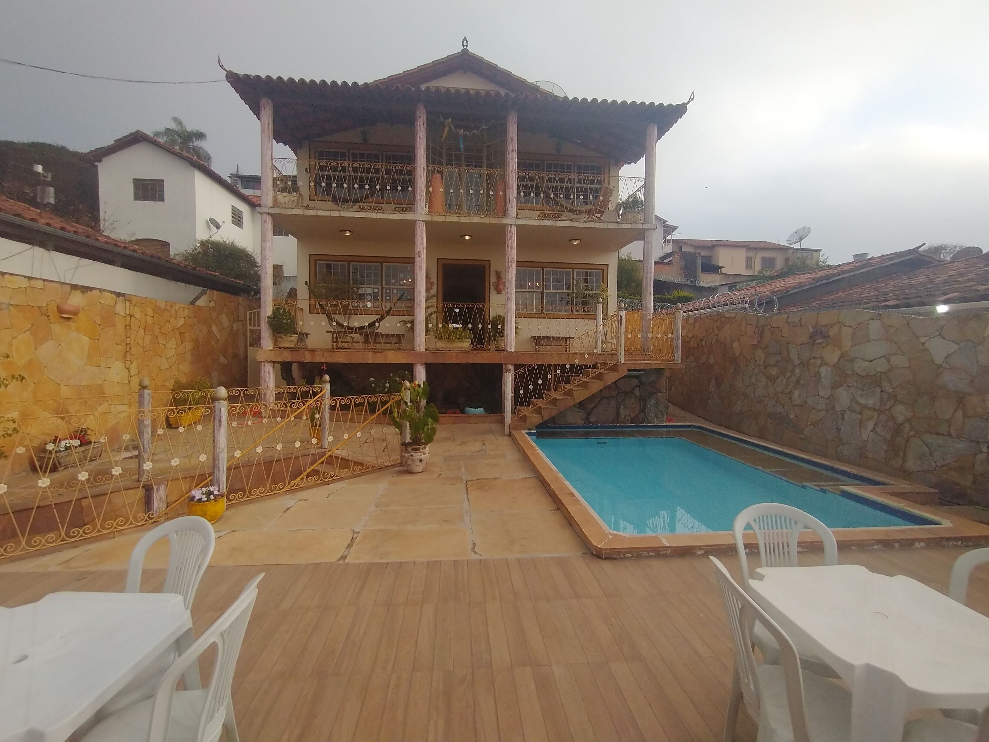 Una casa su due piani con piscina, area salotto esterna e un muro in pietra.