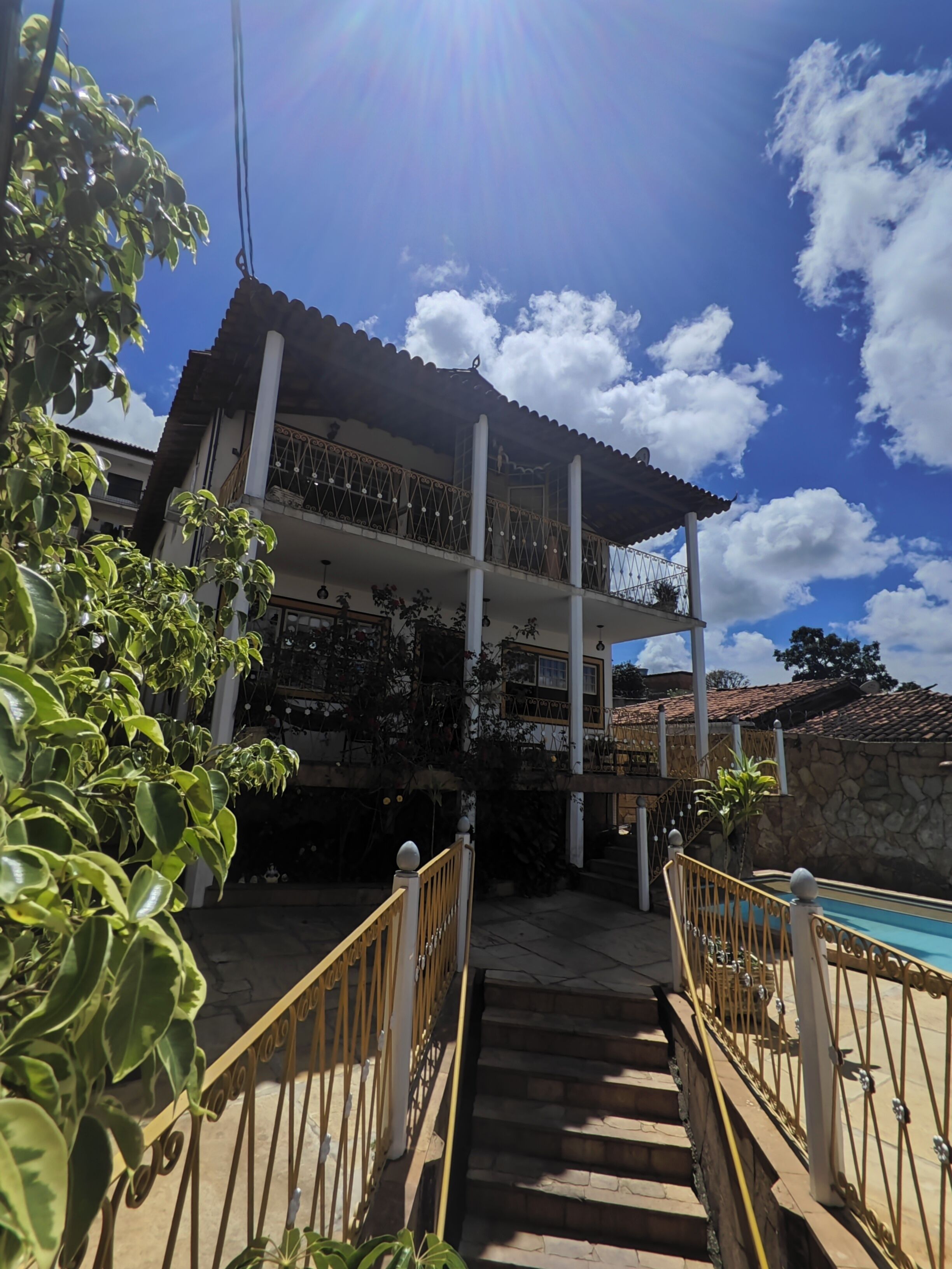 A two-story building with a balcony, a staircase leading to the entrance, and a pool area.