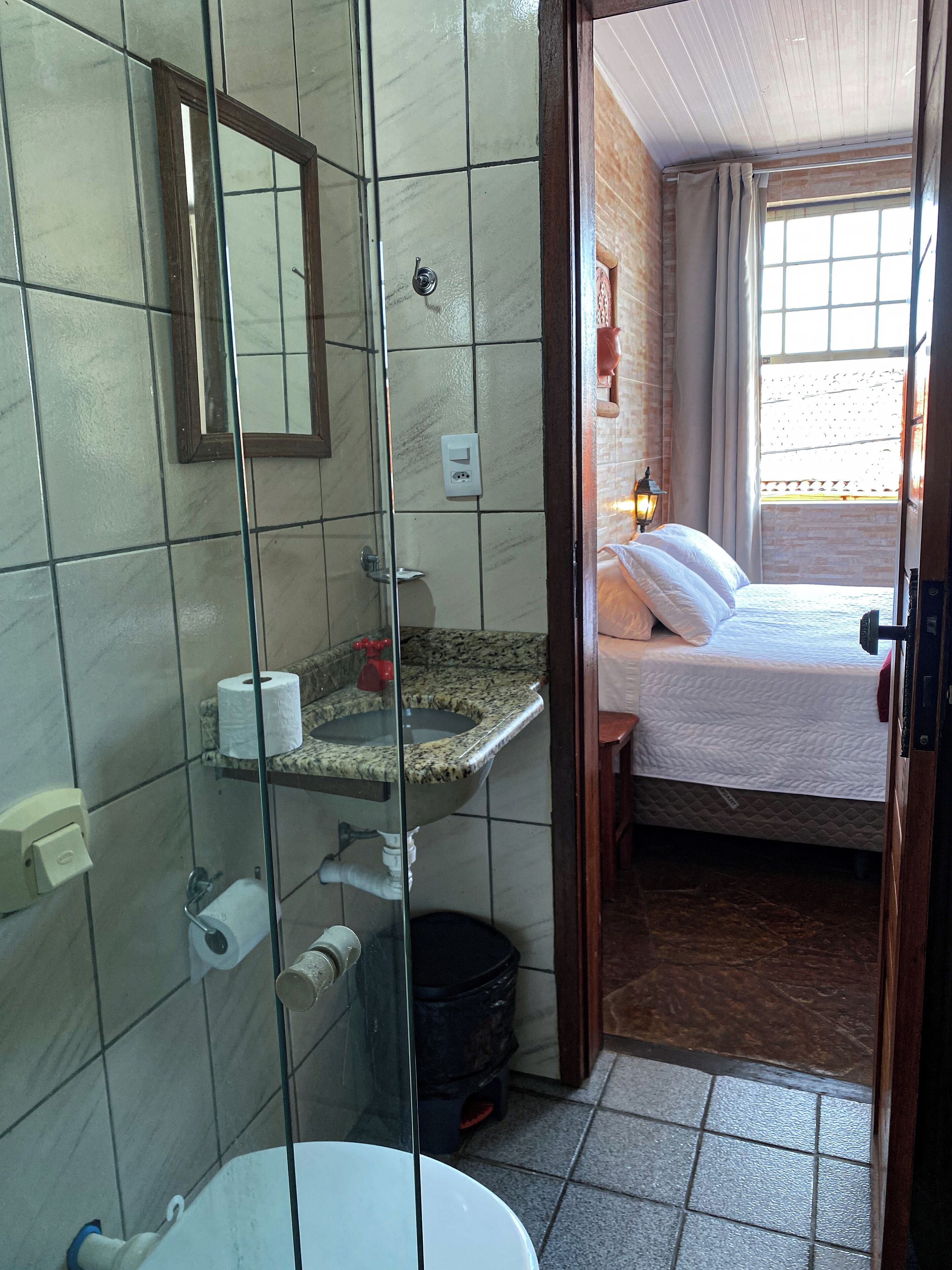 Ein Badezimmer mit Duschkabine aus Glas, einem Waschbecken mit Marmorplatte und einer Toilette.