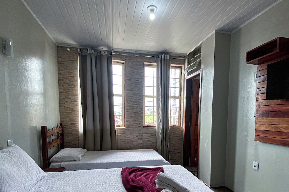 A hotel room with two beds, a brick wall, and a wooden headboard.
