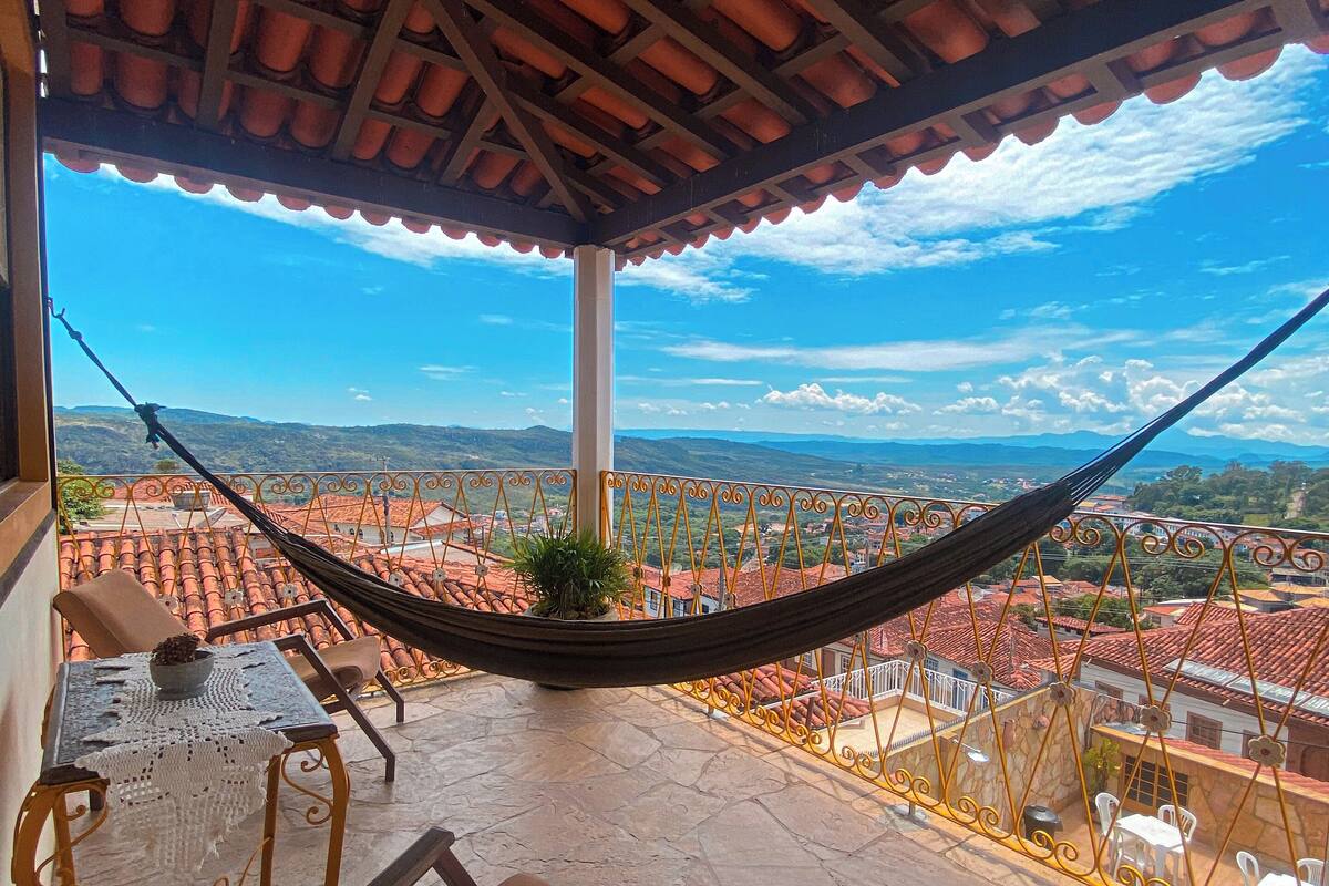 A hammock on a balcony with a view of the cityscape.