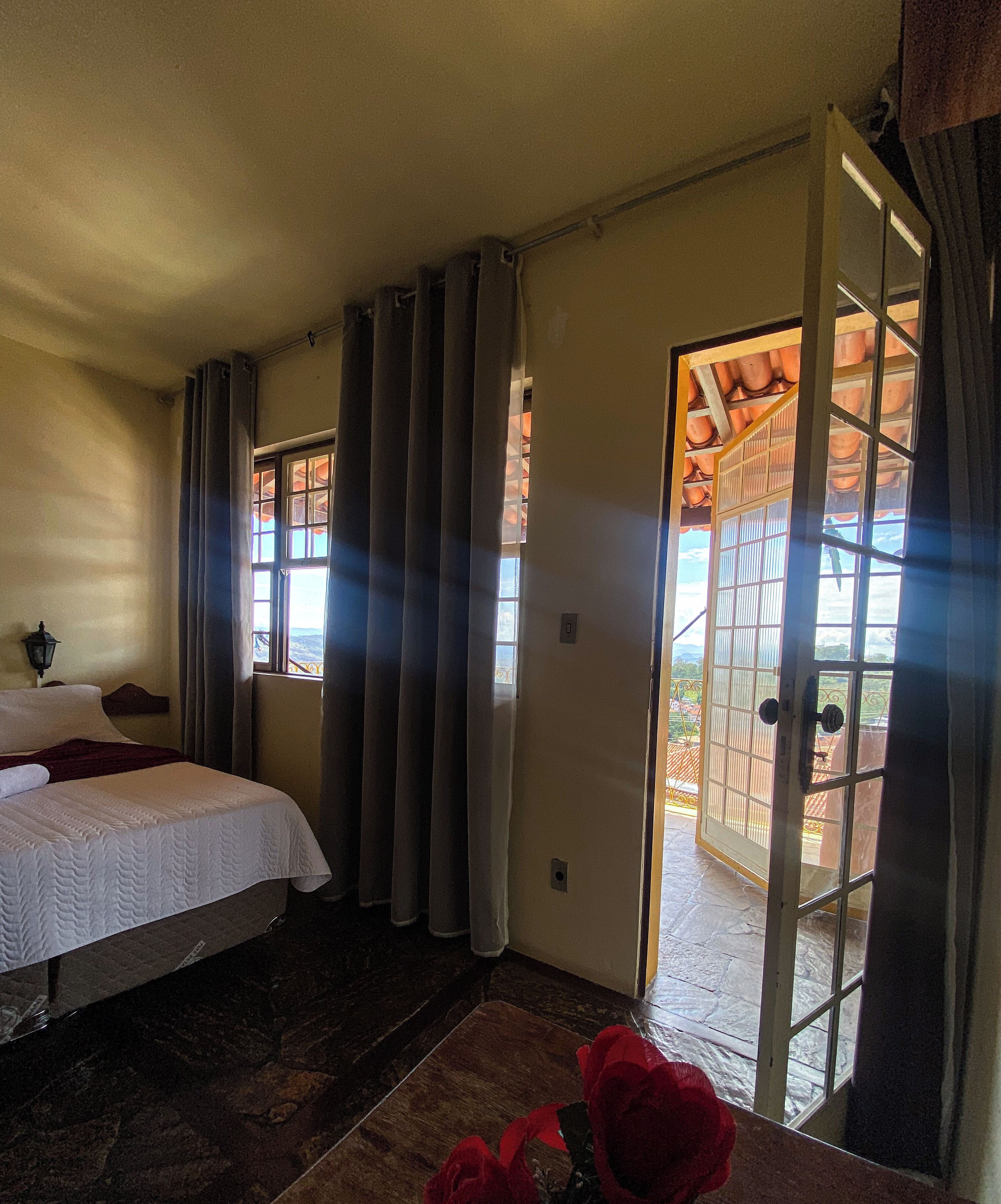 Un dormitorio con cama, cortinas, una ventana y vistas al exterior.