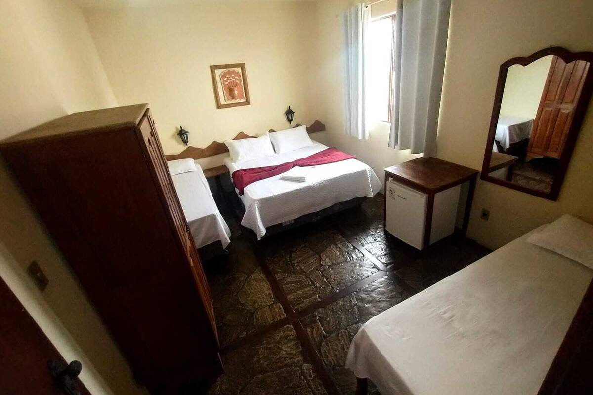 A hotel room with a bed, a desk, a dresser, a mirror, and a window with curtains.