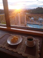 Un balcón con vistas a una piscina y montañas durante el atardecer.