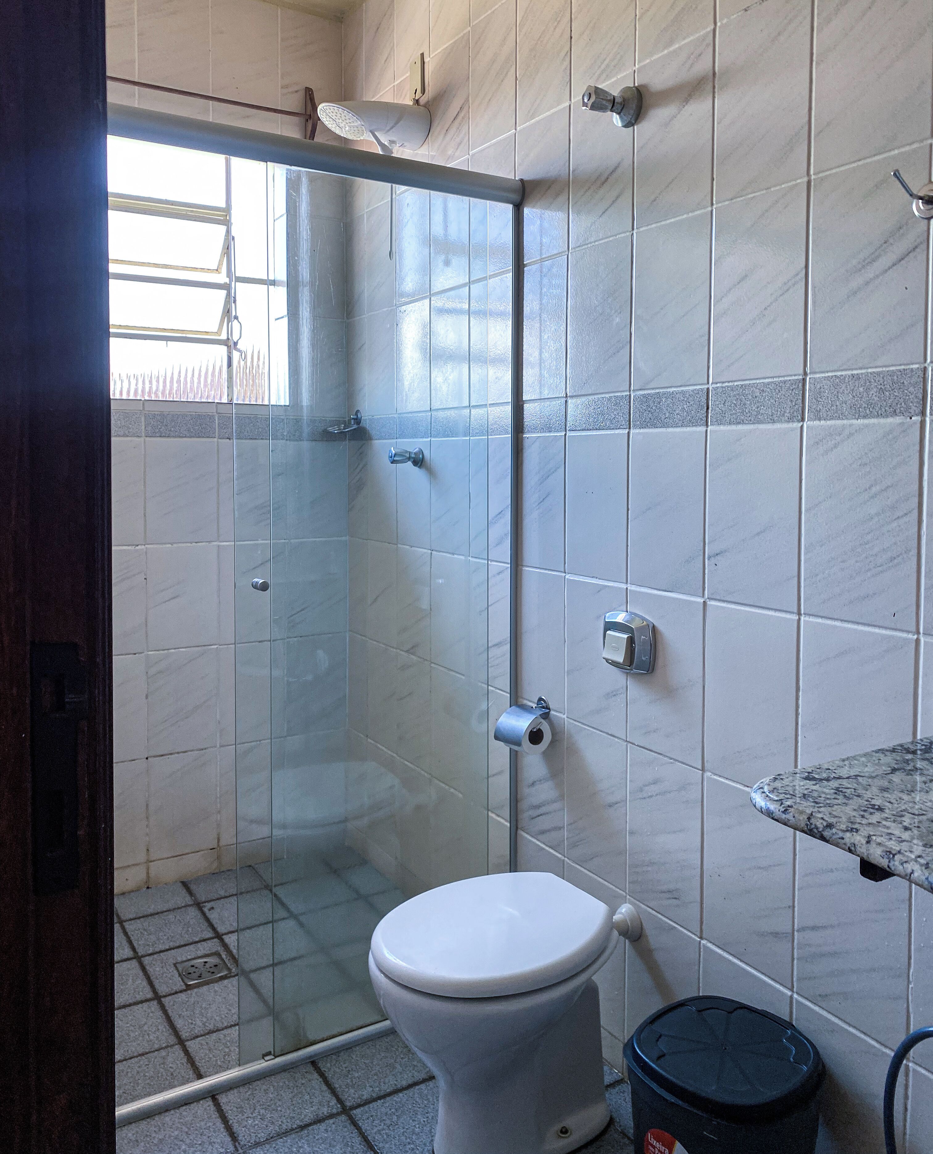 A bathroom with a glass-enclosed shower, a toilet, and a sink.
