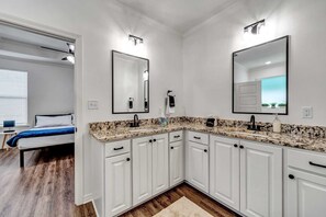 A modern bathroom with white cabinetry, granite countertops, and dual vanity mirrors. - Stay Tyler @ Parade of Homes (Tyler)