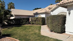 Una propiedad residencial con un césped cuidado, un camino de entrada y una pared exterior blanca.