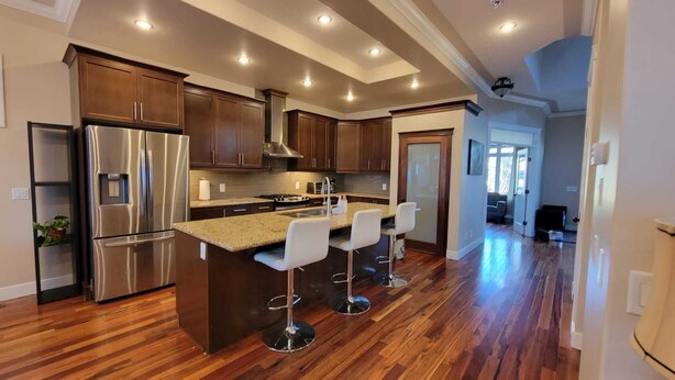 A modern kitchen with wooden cabinets, stainless steel appliances, and a central island with bar stools. - Great house in Inglewood, walking distance to Zoo, Downtown, Restaurants  (Calgary)