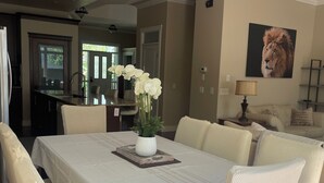 A dining area with a large table, white chairs, a vase of flowers, and a chandelier. - Great house in Inglewood, walking distance to Zoo, Downtown, Restaurants  (Calgary)