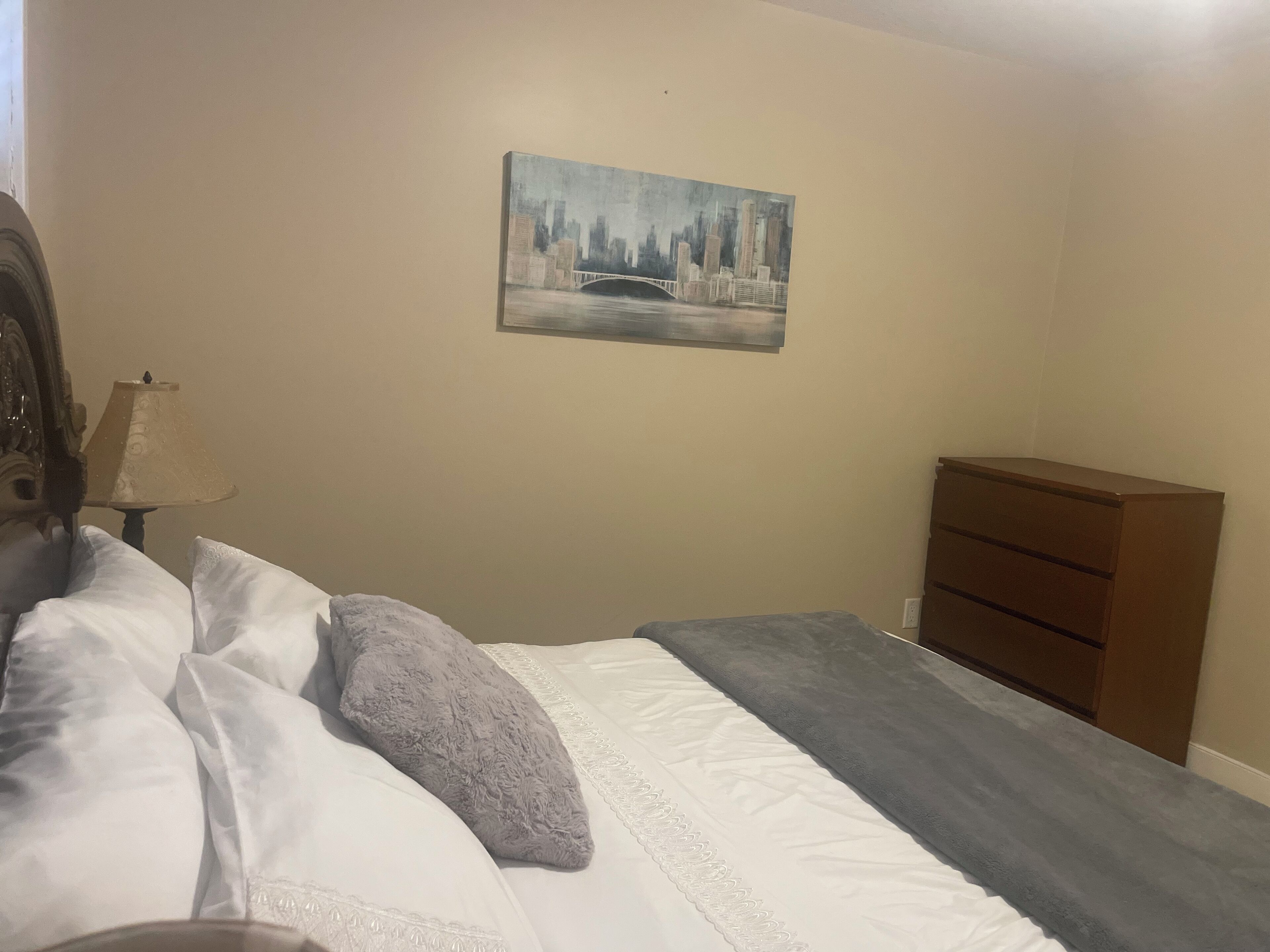 Ein Schlafzimmer mit einem Bett, einem Schminktisch und einem Bild an der Wand.