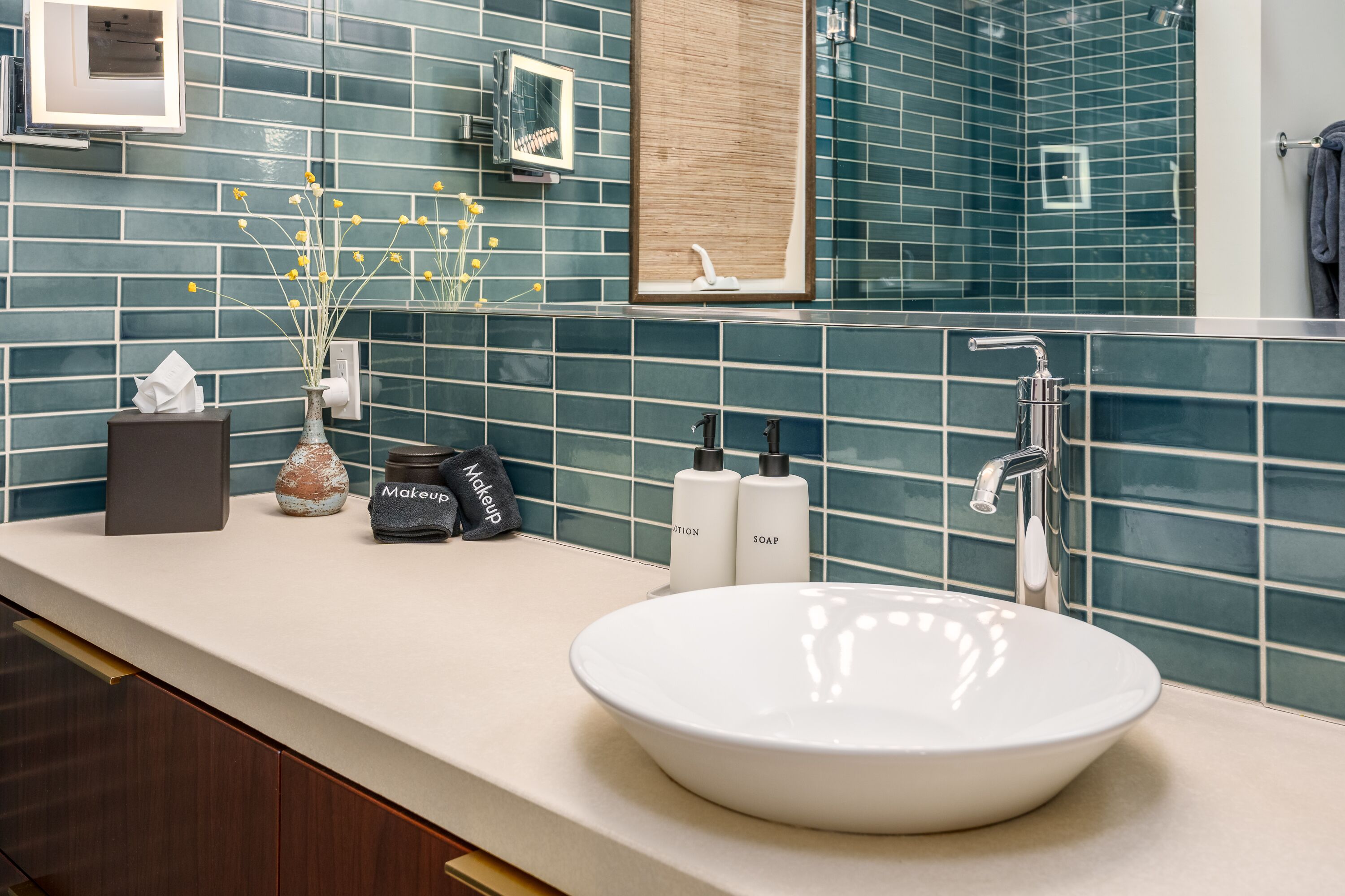 Un bagno con un lavandino bianco, pareti rivestite di piastrelle blu e uno specchio sopra il lavandino.