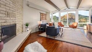 Un salon moderne doté d’une cheminée, de sièges confortables et d’une grande fenêtre offrant une vue panoramique.