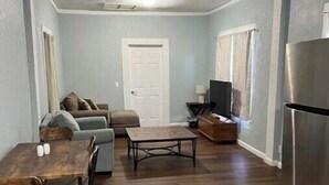 A compact living space with a dining area, a sofa, a television, and a refrigerator. - The Fort Pierce 

 (Fort Pierce)