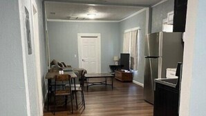 A living room with a dining area, a kitchen with a refrigerator, and a TV. - The Fort Pierce 

 (Fort Pierce)