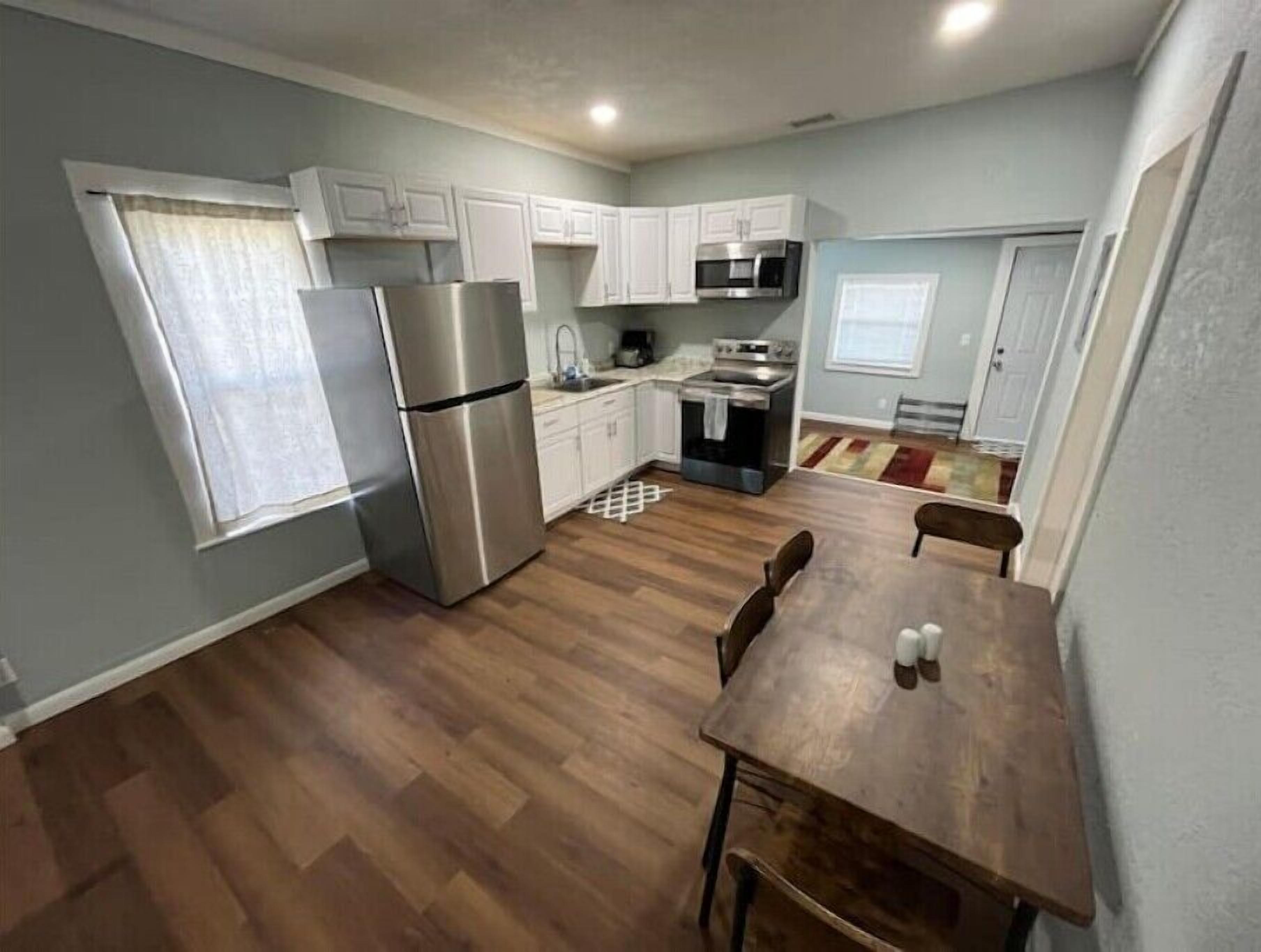 A compact kitchen with white cabinets, a stainless steel refrigerator, a microwave, and an oven.