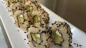 A white rectangular plate with sushi rolls topped with sesame seeds, arranged in a row.