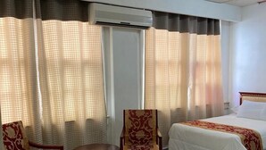 A hotel room with a bed, two chairs, a small table, and a window with curtains. - Hotel Mandarin (Tampico)