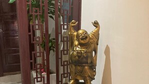 A statue of a laughing Buddha on a wooden pedestal in a hallway. - Hotel Mandarin (Tampico)
