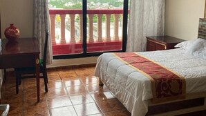 A hotel room with a bed, a desk, and a view of a balcony with a railing. - Hotel Mandarin (Tampico)