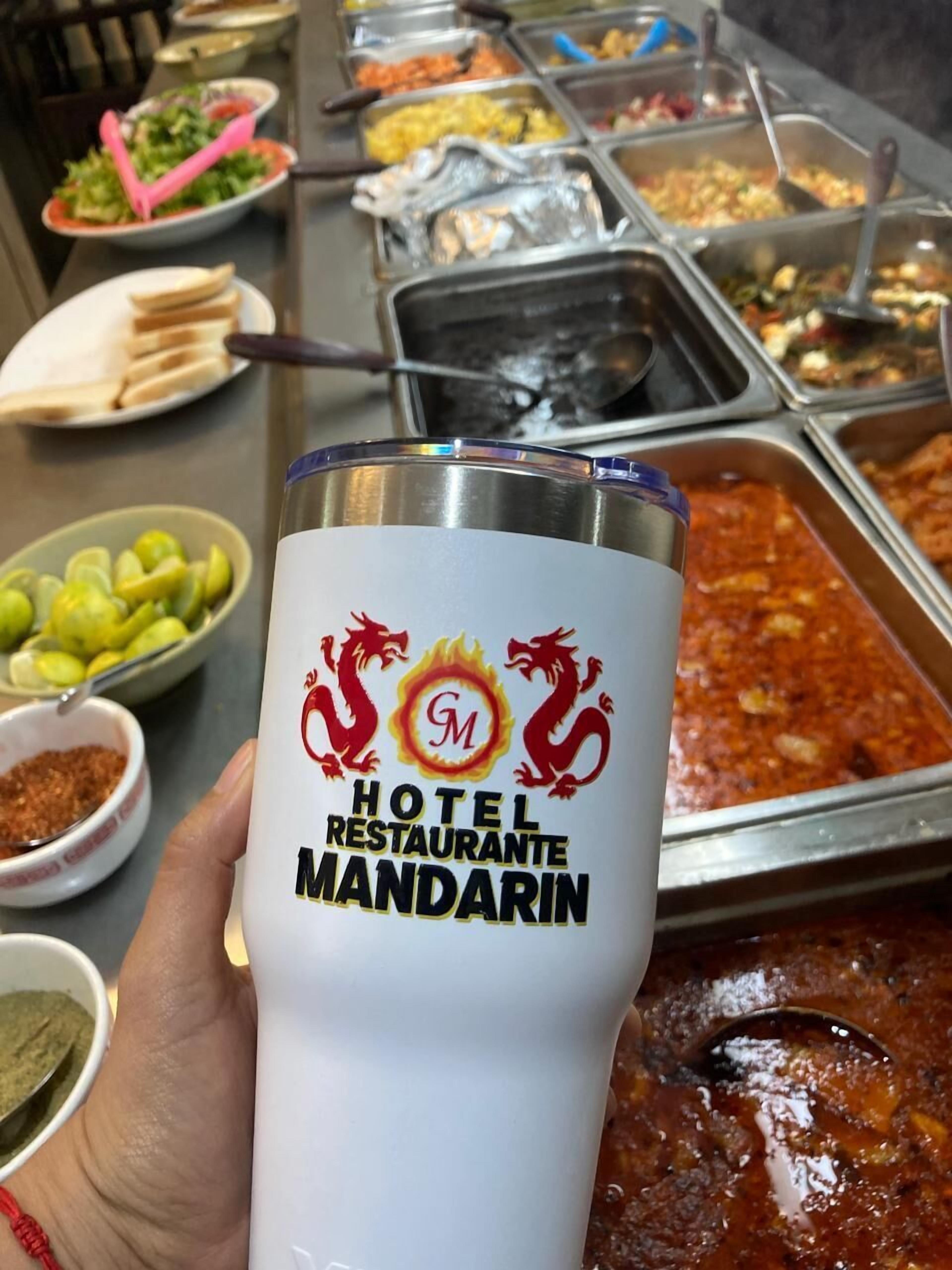 A hand holding a tumbler with the logo of Hotel Restaurante Mandarin.