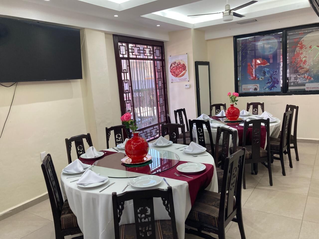 Un comedor con mesas redondas, sillas y un televisor montado en la pared.