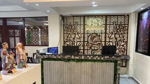 A reception desk with a decorative panel, a television, and a display of figurines. - Hotel Mandarin (Tampico)