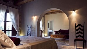 A bedroom with a bed, a wooden chair, a wooden table, and an arched doorway leading to another room. - Villa in Gaffe with 19 bedrooms sleeps 36 (Gaffe)
