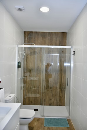A bathroom with a glass-enclosed shower, a toilet, and a sink. - Hostal Garden Rous (Paiporta)