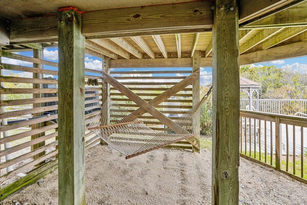 A wooden structure with a hammock and a metal gate.