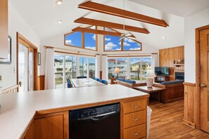 A spacious kitchen with wooden cabinets, a dishwasher, and a large dining area with a view of the neighborhood.