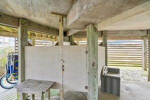 A covered outdoor area with a wooden table and benches, a bicycle rack, and a trash bin.