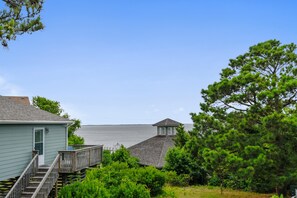 Une propriété située sur la côte, avec un escalier en bois menant à une maison, une petite tour et une vue sur la mer.