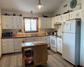 A kitchen with white cabinets, a microwave, a stove, and a refrigerator. - Hurricane Charlie's --Pet Friendly home with Water Views and Community Amenities (Duck)