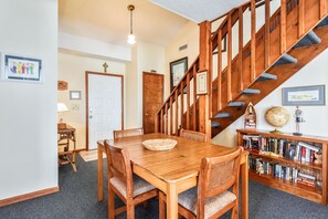 Ein Essbereich mit einem Holztisch, Stühlen, einem Bücherregal und einer Treppe.