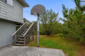 A basketball hoop with a sign reading 'HURRICANE CHARLIES' in a residential setting with a staircase leading to a house.