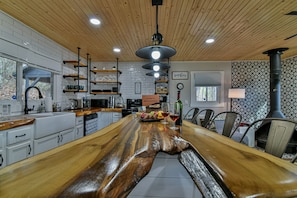 A kitchen with a central island, wooden ceiling, white tiled backsplash, and various kitchen appliances.