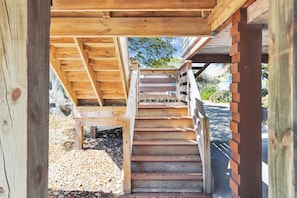 Una escalera de madera que conduce a un espacio cubierto con un muro de ladrillo.