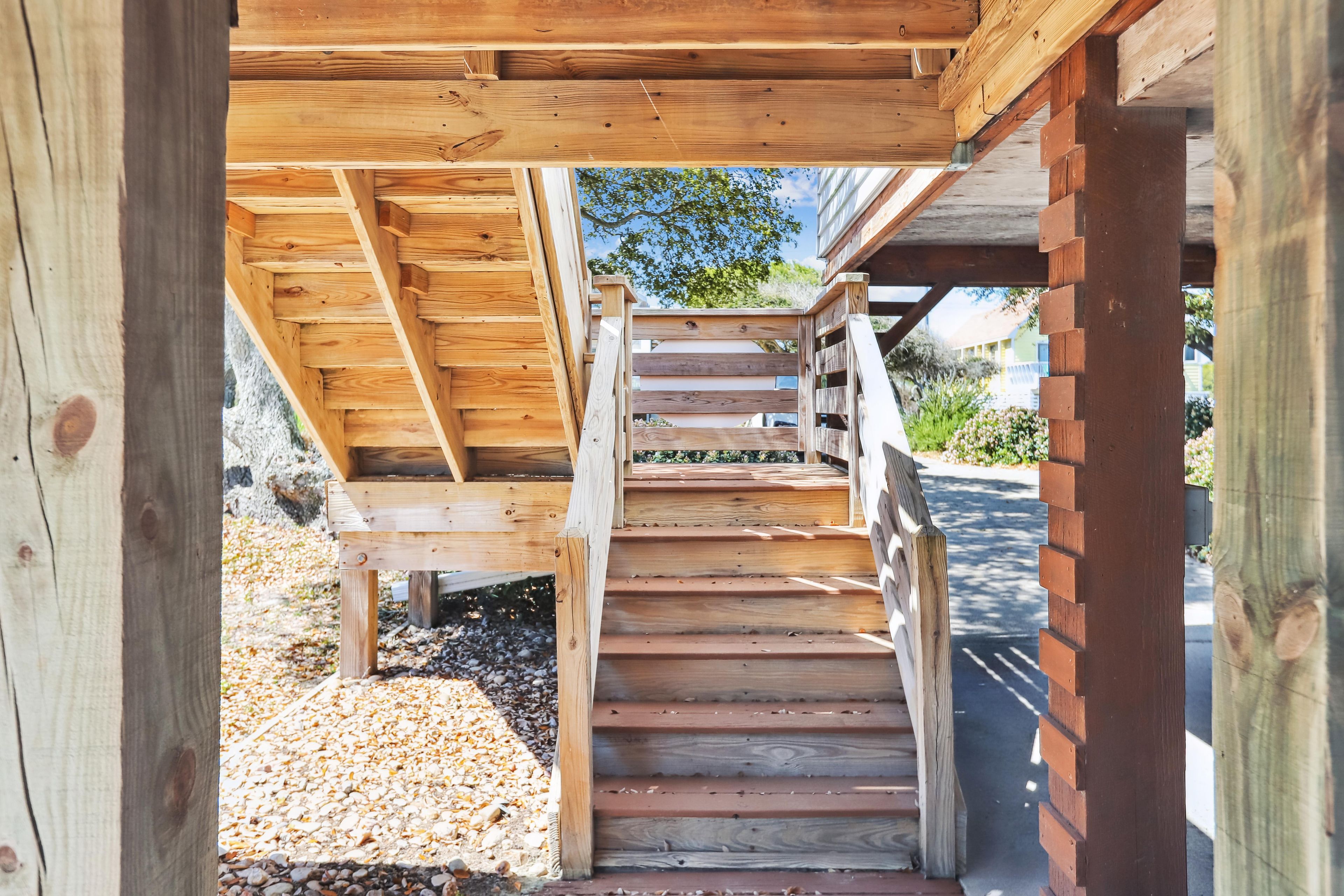 Eine Holztreppe führt zu einem überdachten Bereich, an dessen Seite eine Backsteinmauer steht.