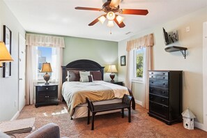 Cozy retreat with a large bed, bedside tables, and a ceiling fan above.