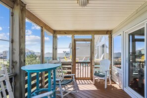 Enjoy meals and relaxation in this outdoor space with a table and chairs, surrounded by a large window view.