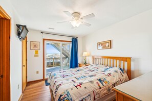 Quarto com cama, ventoinha no teto, janela com vista e porta.