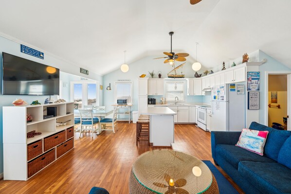 A modern kitchen with white cabinets, a central island, and a dining area with a table and chairs.