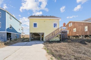 A coastal property with a wooden deck, a covered entrance, and a clear sky.