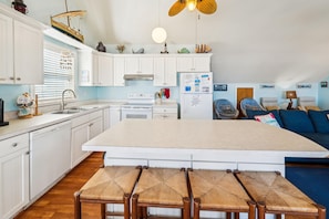 A kitchen with white cabinets, a central island, and a dining area with wicker chairs.