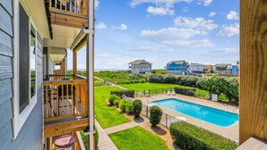 A residential area with a swimming pool, a grassy lawn, and a view of houses in the background. - Duck Legacy -- 3BR Oceanfront Condo 2nd Floor with Ocean Views (Duck)
