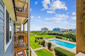 A residential area with a swimming pool, a grassy lawn, and a view of houses in the background. - Duck Legacy -- 3BR Oceanfront Condo 2nd Floor with Ocean Views (Duck)