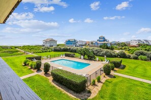 Área residencial com piscina, cercada por gramados e sebes bem cuidadas.