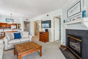 Una sala de estar con chimenea, televisor y comedor con mesa de madera.